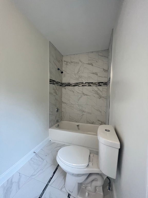 bathroom with tiled shower / bath combo and toilet