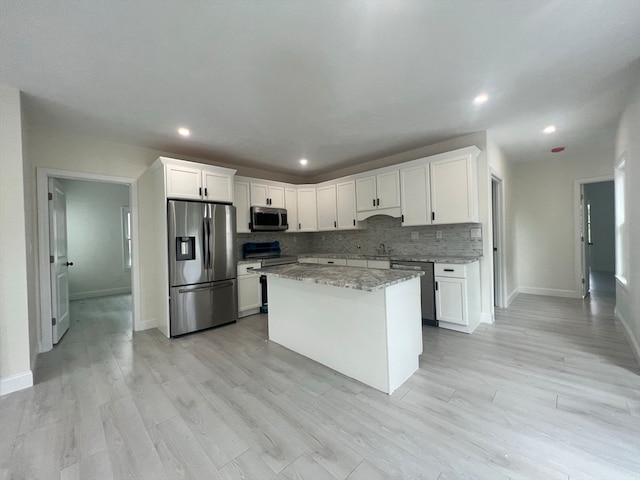 kitchen featuring light stone countertops, stainless steel appliances, light hardwood / wood-style flooring, and white cabinetry