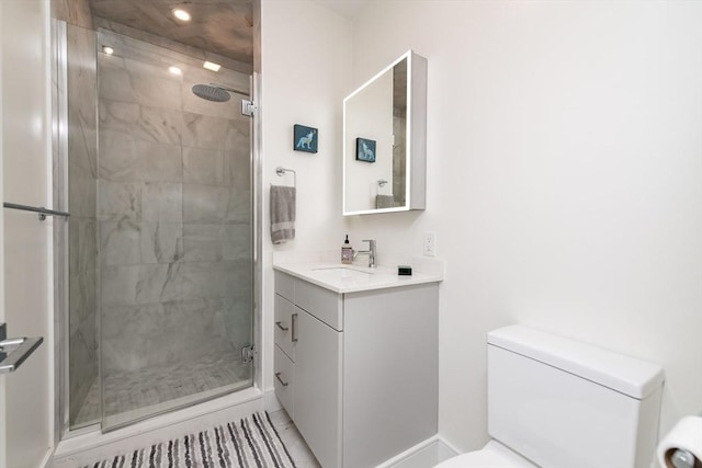 bathroom with toilet, vanity, and a shower with door