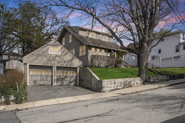 view of front of home featuring driveway, fence, a yard, and a garage
