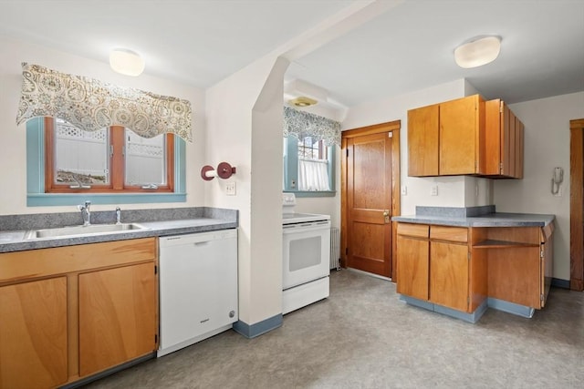 kitchen with light floors, brown cabinetry, a sink, and white appliances