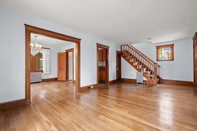 unfurnished living room with baseboards, light wood-style floors, stairway, and radiator