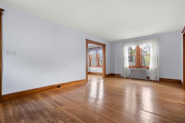 unfurnished room with radiator, wood-type flooring, and baseboards
