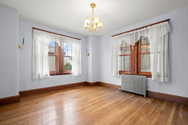 unfurnished room featuring baseboards, radiator heating unit, hardwood / wood-style flooring, and a notable chandelier