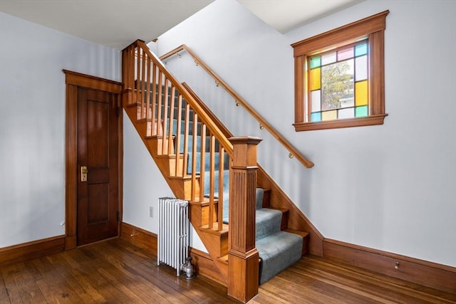 staircase featuring hardwood / wood-style flooring, baseboards, and radiator heating unit