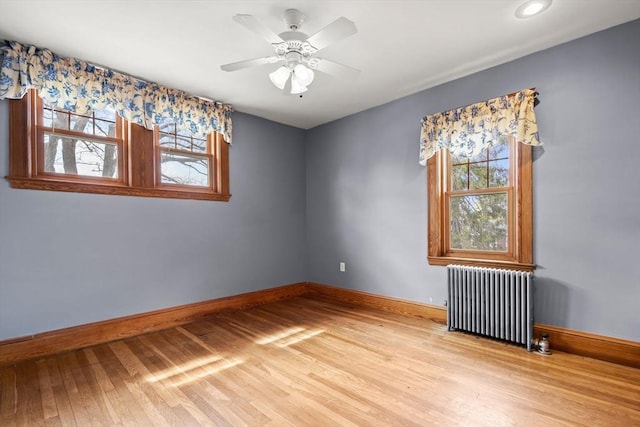 empty room featuring radiator heating unit, baseboards, recessed lighting, and light wood-style floors