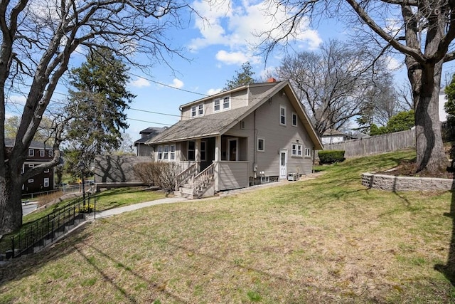rear view of property with a lawn, a porch, and fence