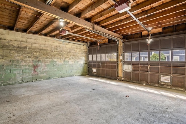 garage featuring a garage door opener and concrete block wall