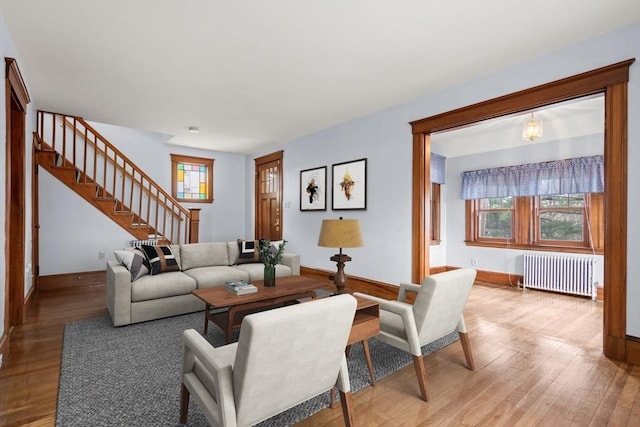 living room with radiator heating unit, baseboards, stairs, and a healthy amount of sunlight