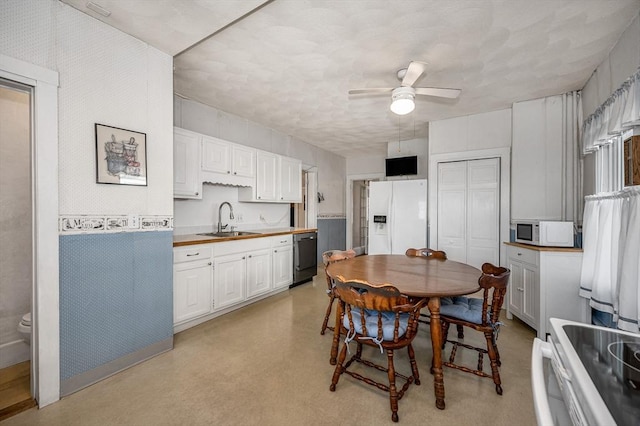 kitchen with butcher block countertops, sink, white appliances, ceiling fan, and white cabinets