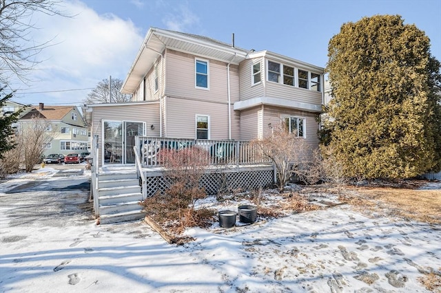 snow covered house with a wooden deck