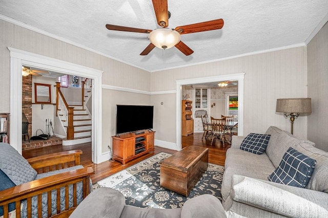 living room featuring crown molding, wood-type flooring, a textured ceiling, and ceiling fan