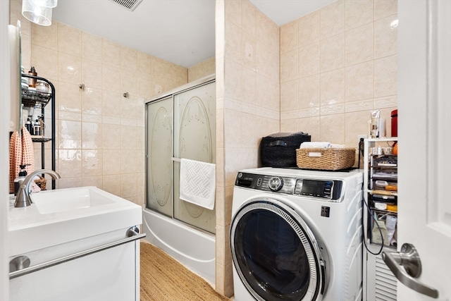 clothes washing area featuring tile walls, sink, and washer / dryer