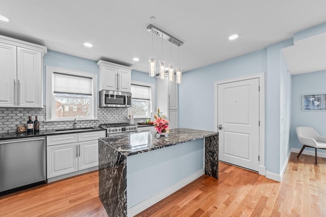 kitchen featuring sink, a center island, decorative light fixtures, white cabinets, and appliances with stainless steel finishes