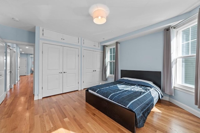 bedroom with multiple closets and light hardwood / wood-style flooring