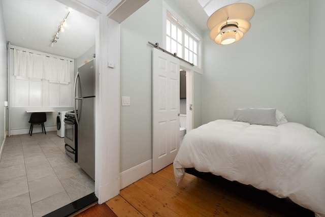 1411 Washington St Unit 7, Boston, MA 02118 - bedroom featuring baseboards, a barn door, freestanding refrigerator, rail lighting, and light wood-type flooring