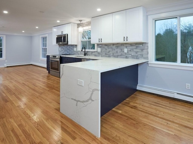 kitchen featuring hanging light fixtures, appliances with stainless steel finishes, white cabinets, and kitchen peninsula