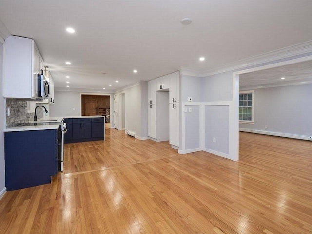 kitchen with sink, crown molding, blue cabinetry, white cabinetry, and light wood-type flooring