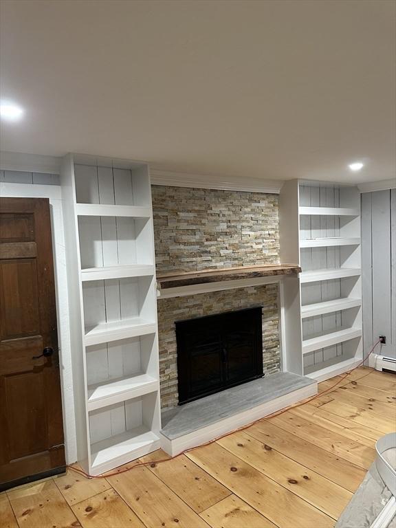 unfurnished living room featuring a fireplace, light hardwood / wood-style floors, and built in shelves