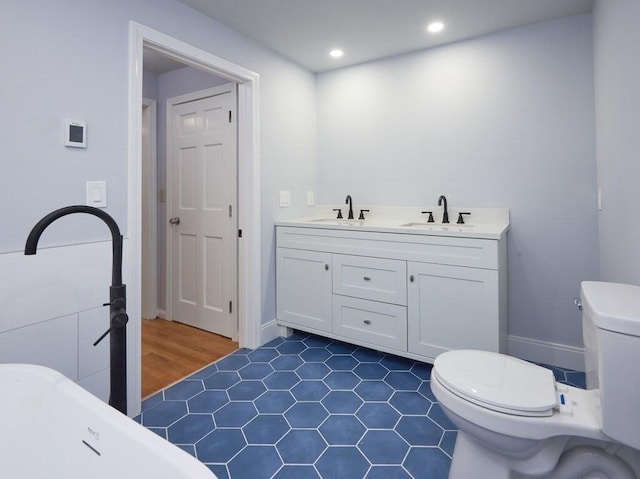 bathroom featuring a tub to relax in, vanity, and toilet