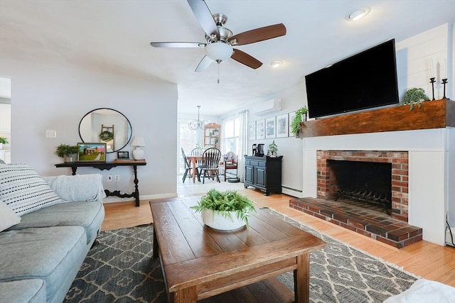 living room with light hardwood / wood-style floors, a baseboard heating unit, a wall unit AC, and a fireplace