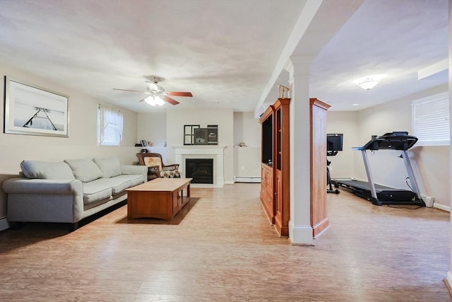 living room featuring ornate columns, ceiling fan, a baseboard radiator, and light hardwood / wood-style floors