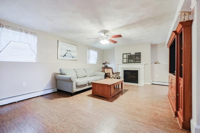 living room with a baseboard radiator, light wood-type flooring, and ceiling fan