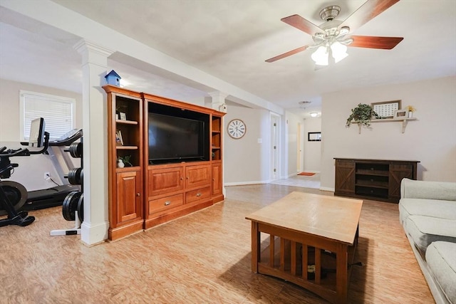 living room featuring decorative columns, ceiling fan, and light wood-type flooring