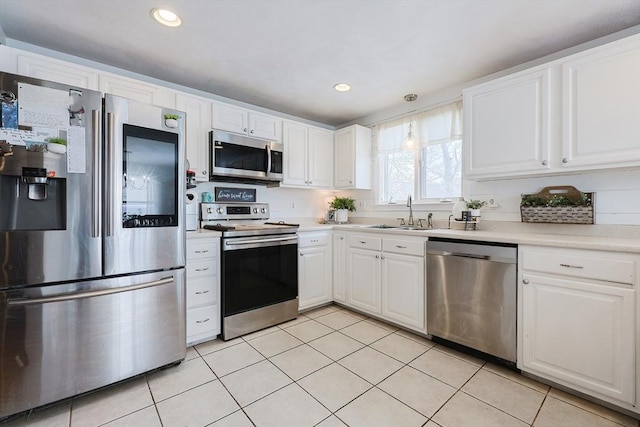 kitchen featuring sink, white cabinets, light tile patterned floors, and stainless steel appliances