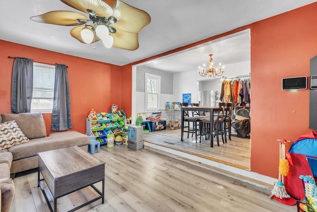 living room with a healthy amount of sunlight, ceiling fan with notable chandelier, and light wood-type flooring