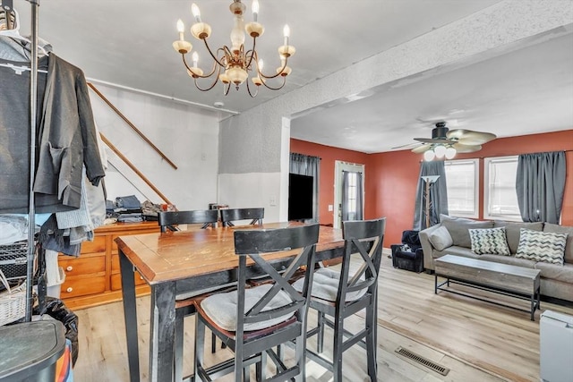 dining space with ceiling fan with notable chandelier and light wood-type flooring