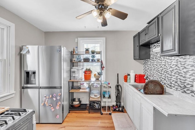 kitchen featuring stainless steel refrigerator with ice dispenser, sink, light wood-type flooring, ceiling fan, and decorative backsplash