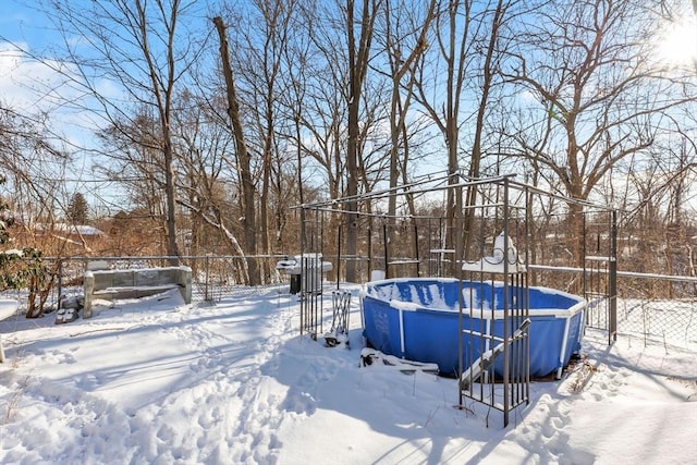 yard layered in snow with a fenced in pool