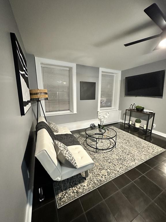 living area featuring ceiling fan, baseboards, and tile patterned floors