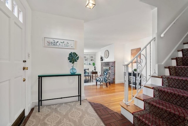 foyer featuring a brick fireplace and hardwood / wood-style floors