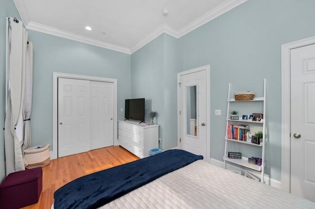 bedroom with a closet, baseboards, wood finished floors, and crown molding