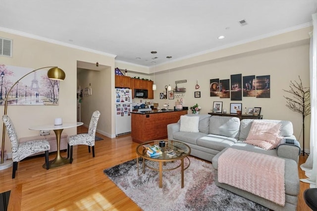 living area featuring recessed lighting, light wood-style floors, baseboards, and ornamental molding