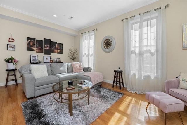 living room with visible vents, crown molding, baseboards, and wood finished floors