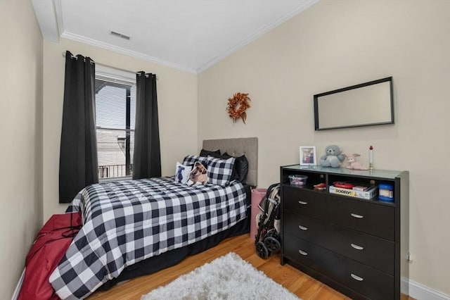 bedroom featuring visible vents, baseboards, light wood-style floors, and ornamental molding