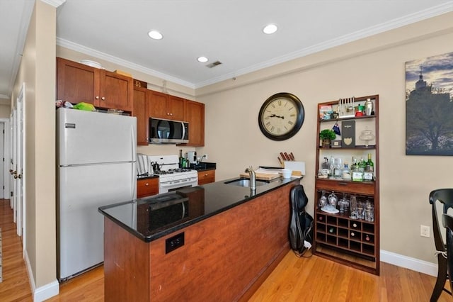 kitchen with crown molding, light wood-type flooring, brown cabinets, white appliances, and a sink