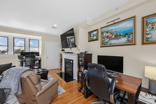 office area featuring visible vents, a fireplace with flush hearth, recessed lighting, ornamental molding, and light wood-type flooring