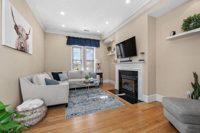 living room featuring a fireplace with flush hearth, light wood-style flooring, baseboards, and ornamental molding