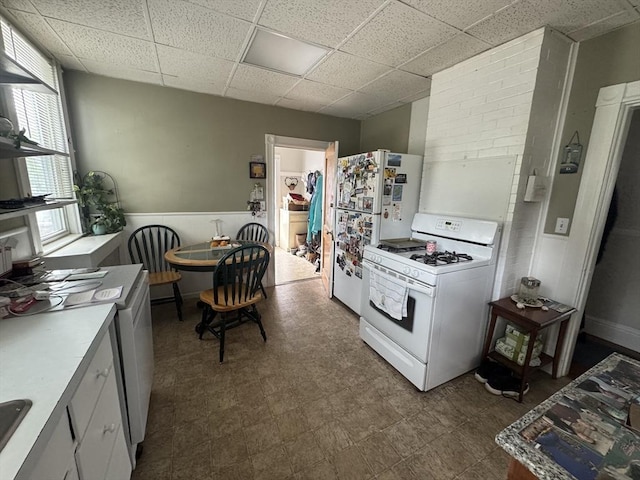 39 Newbury Ave, Quincy, MA 02171 - kitchen with white appliances, a drop ceiling, dark flooring, light countertops, and wainscoting