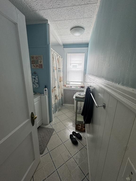 39 Newbury Ave, Quincy, MA 02171 - full bathroom featuring a wainscoted wall, curtained shower, and tile patterned flooring