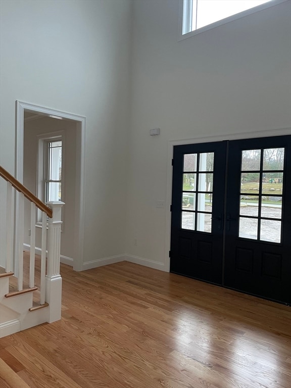 foyer with french doors, light hardwood / wood-style flooring, and a high ceiling