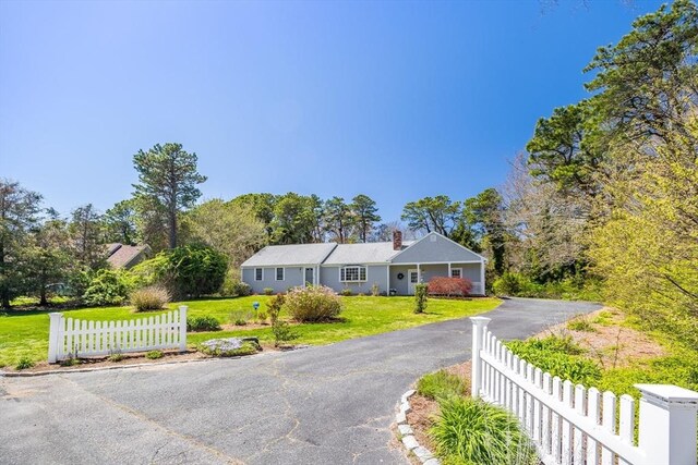 ranch-style home with a front lawn, fence, and driveway