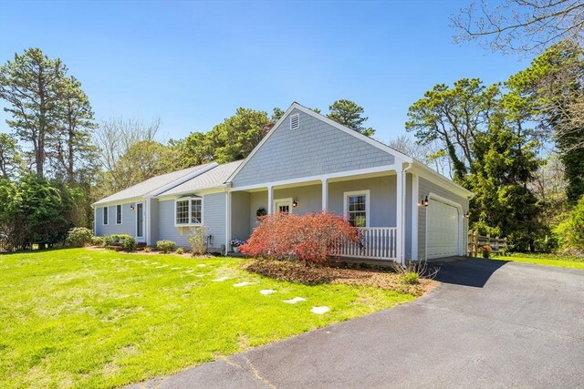 view of front of home with an attached garage, driveway, a front yard, and a porch