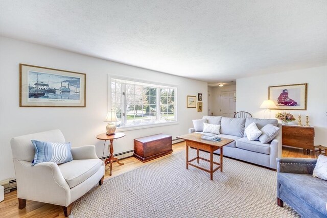 living area with a textured ceiling, a baseboard radiator, baseboard heating, and wood finished floors