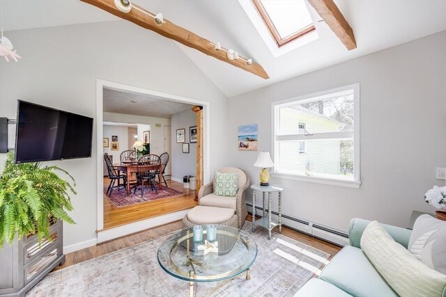 living room with vaulted ceiling with skylight, baseboards, a baseboard radiator, and wood finished floors