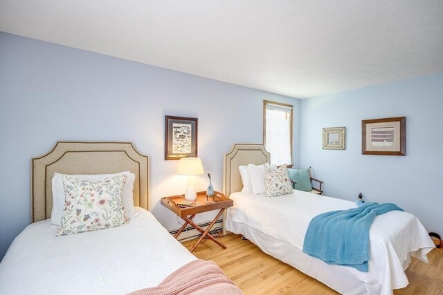bedroom with wood finished floors and baseboard heating